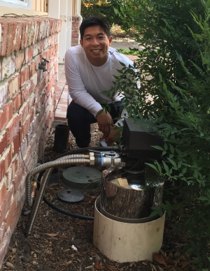 a happy customer (Eric Toda) sitting next to his water tank